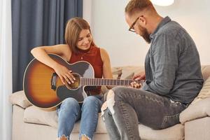 profesor de guitarra que muestra cómo tocar el instrumento a una mujer joven foto