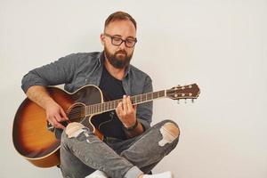 en el estudio. el hombre con ropa informal y con guitarra acústica está en el interior foto