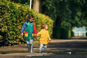 Walking together. Kids having fun outdoors in the park after the rain photo