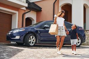 With shopping bags. Woman with little boy near the the modern automobile at daytime photo