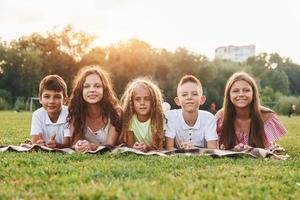 Front view. Group of happy kids is outdoors on the sportive field at daytime photo