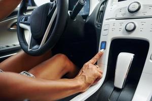 Close up view of front control panel. Woman in casual clothes is sitting in her automobile at daytime photo