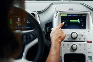 Close up view of front control panel. Woman in casual clothes is sitting in her automobile at daytime photo