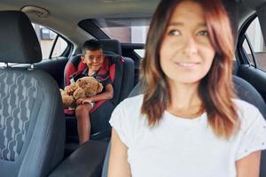 Front view. Woman with little boy is in the modern automobile at daytime photo