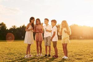 Illuminated by sunlight. Standing on the sportive field. Group of happy kids is outdoors at daytime photo