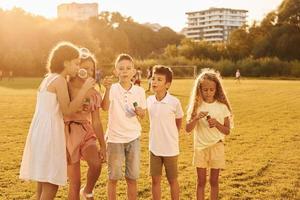 Illuminated by sunlight. Standing on the sportive field. Group of happy kids is outdoors at daytime photo