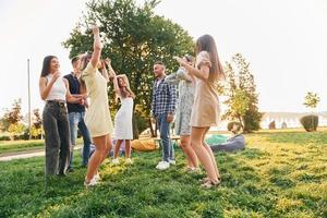 feliz gasto de tiempo de fin de semana. grupo de jóvenes tienen una fiesta en el parque durante el día de verano foto