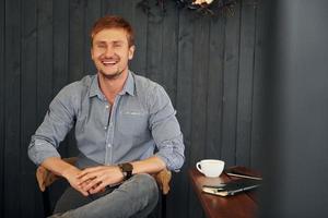 Facial expression. Adult man is sitting indoors by the table in the cafe photo