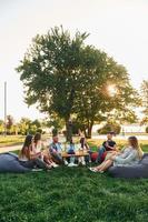 hablando unos con otros. grupo de jóvenes tienen una fiesta en el parque durante el día de verano foto