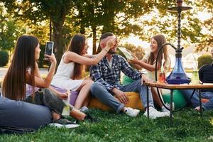 Drinking game. Group of young people have a party in the park at summer daytime photo