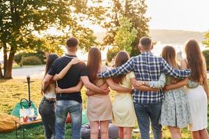 View from behind. Group of young people have a party in the park at summer daytime photo