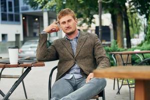 Adult man sitting outdoors at the cafe table at daytime photo