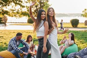 mujeres posando para la cámara. grupo de jóvenes tienen una fiesta en el parque durante el día de verano foto