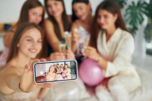 Holding glasses with drink. Group of happy women that is at a bachelorette party photo