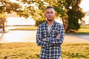 Man with arms crossed standing in the park at daytime photo