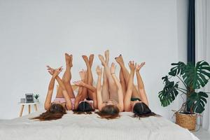 Laying down on bed with legs up. Group of happy women that is at a bachelorette party photo