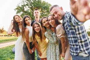 Taking a selfie. Group of young people have a party in the park at summer daytime photo