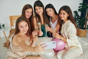 sosteniendo vasos con bebida. grupo de mujeres felices que está en una despedida de soltera foto