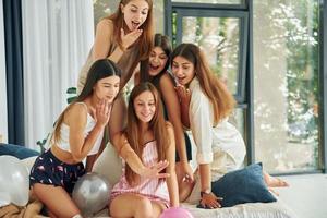 descansando en la cama. grupo de mujeres felices que está en una despedida de soltera foto