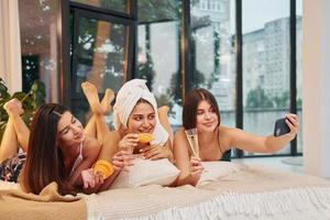 Laying down on bed with slices of orange. Group of happy women that is at a bachelorette party photo