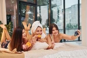 acostado en la cama con rodajas de naranja. grupo de mujeres felices que está en una despedida de soltera foto