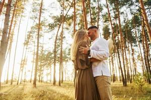 el hombre está en camisa blanca y la mujer en vestido. pareja feliz está al aire libre en el bosque durante el día foto