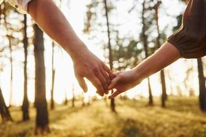 Close up view of hands. Happy couple is outdoors in the forest at daytime photo