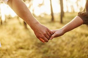 vista enfocada de las manos. pareja feliz está al aire libre en el bosque durante el día foto