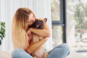 Embracing the pet. Woman with pug dog is at home at daytime photo