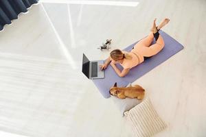 Top view of woman with pug dog and laptop that is at home at daytime photo