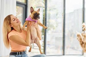 Embracing the pet. Woman with pug dog is at home at daytime photo