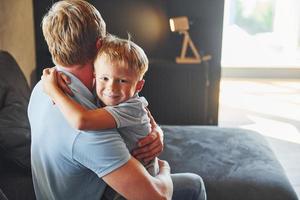 niño abrazando a su padre. padre e hijo están juntos en casa en el interior foto