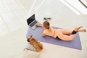 Top view of woman with pug dog and laptop that is at home at daytime photo