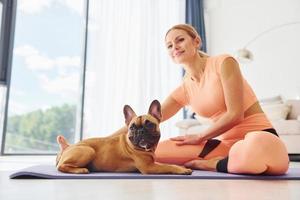 tiempo de yoga mujer con perro pug está en casa durante el día foto