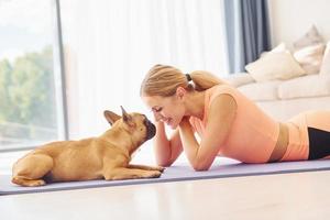 Laying down on the mat. Woman with pug dog is at home at daytime photo