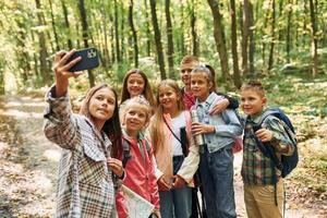 Front view. Kids in green forest at summer daytime together photo