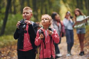 Having a walk. Kids in green forest at summer daytime together photo