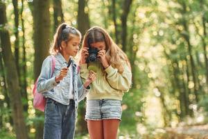 Two friends. Kids in green forest at summer daytime together photo