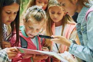 With map. Kids in green forest at summer daytime together photo