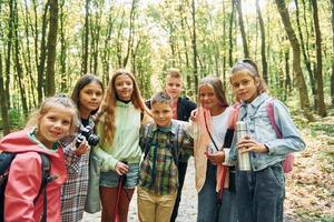 Standing together. Kids in green forest at summer daytime together photo