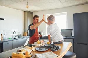 Preparing some food. Father and son is indoors at home together photo