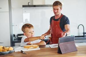 Using tablet to learn how to cook. Father and son is indoors at home together photo