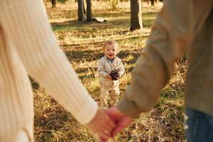 gente joven. feliz familia de padre, madre e hija pequeña está en el bosque foto