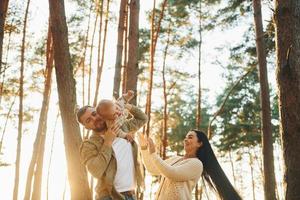 Alegría y felicidad. familia de padre, madre e hija pequeña está en el bosque foto