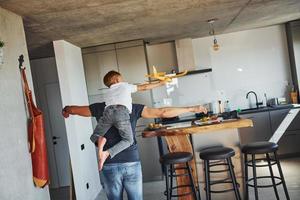 Playing with yellow toy plane. Father and son is indoors at home together photo