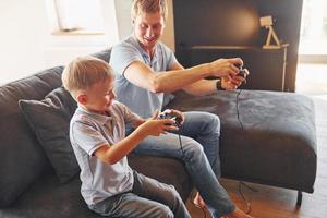 con joysticks de videojuegos. padre e hijo están juntos en casa en el interior foto