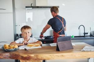 aprendiendo a cocinar. padre e hijo están juntos en casa en el interior foto