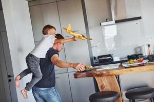 Playing with yellow toy plane. Father and son is indoors at home together photo