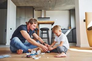 Playing with constructor. Father and son is indoors at home together photo