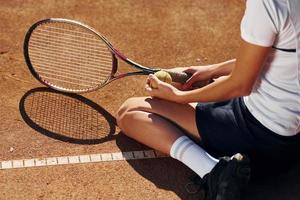 On the ground. Female tennis player is on the court at daytime photo